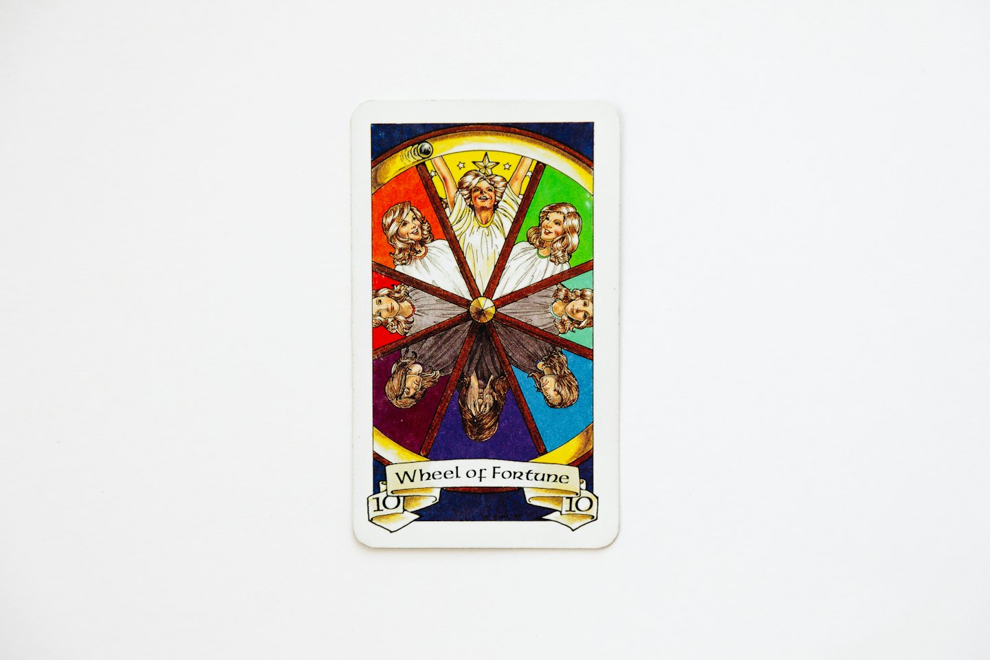 The Wheel of Fortune tarot card rests on a white surface.